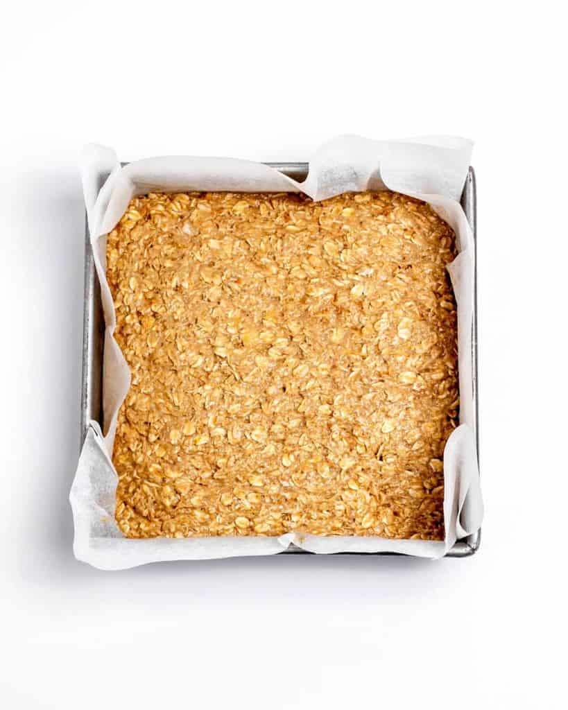 Unbaked banana oat mixture pressed down into a square baking pan.