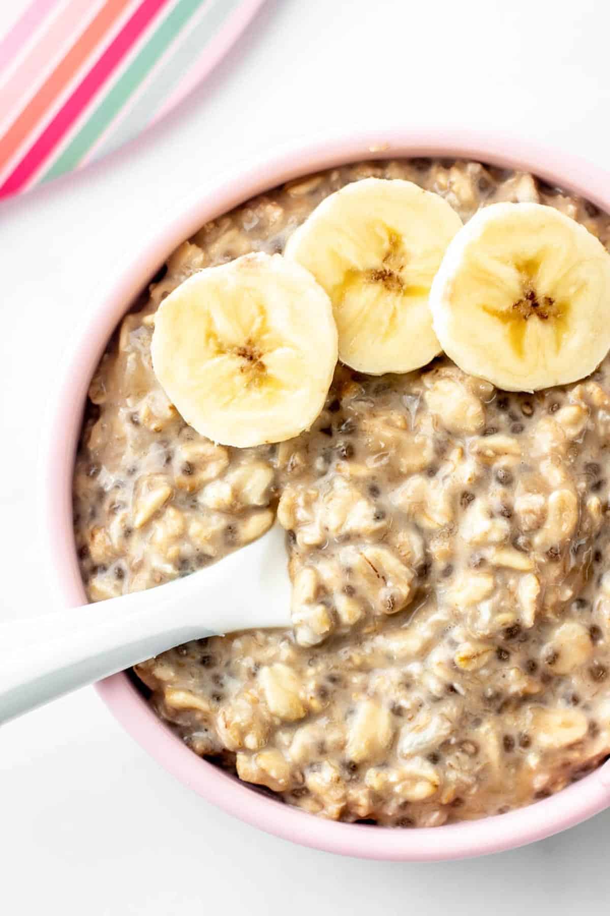 A close up of BLW overnight oats in a bowl topped with three banana slices.