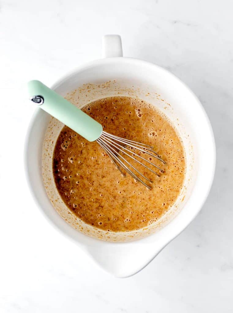 The wet ingredients being whisked together in a white bowl.