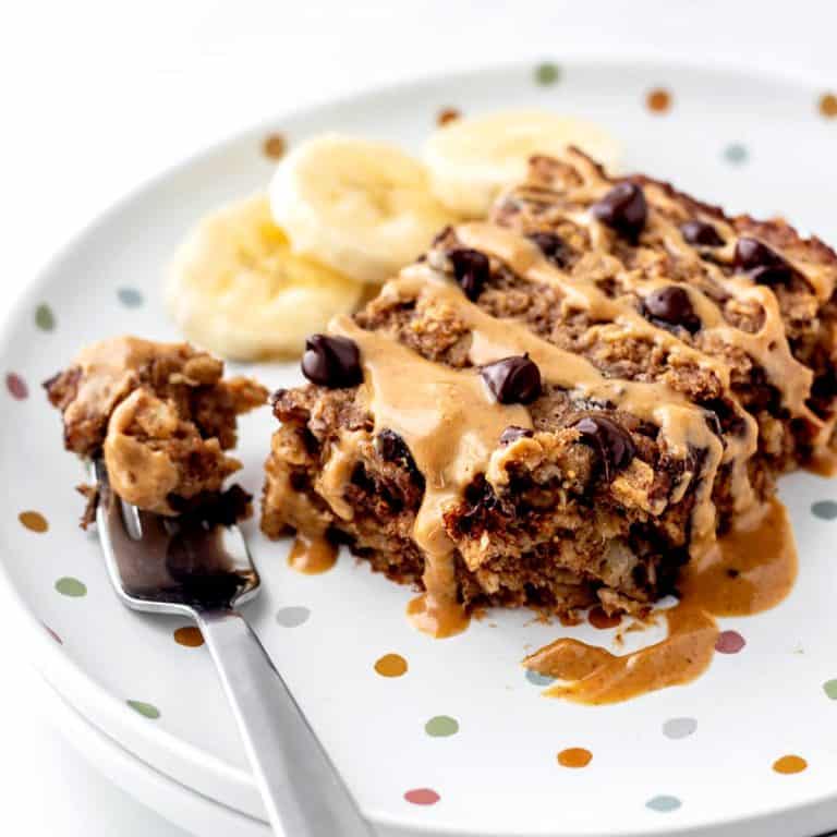 A piece of baked chocolate chip oatmeal beside a fork with some baked oatmeal on it.