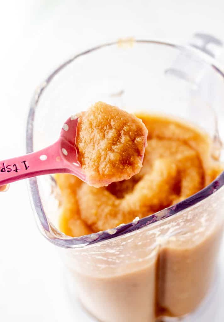 A spoon holding up some freshly made applesauce.