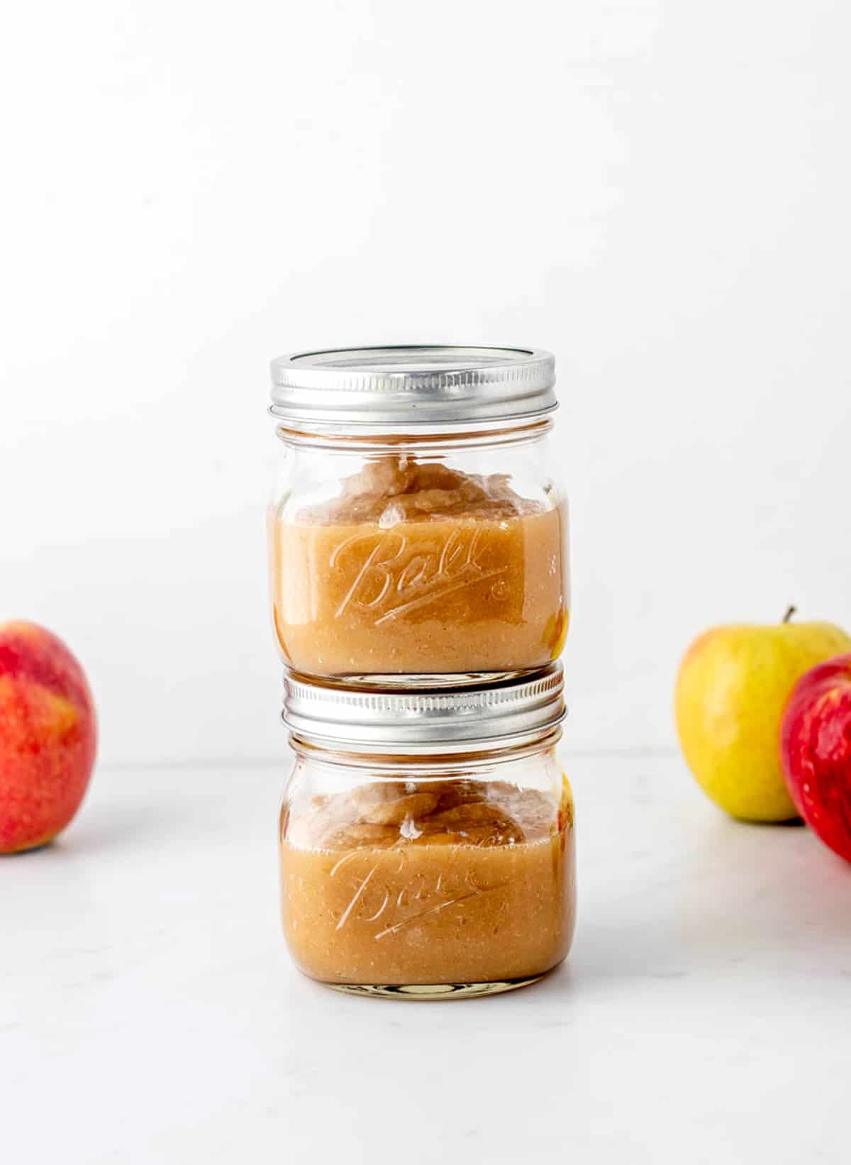 Two jars of homemade unsweetened applesauce stacked on top of each other.