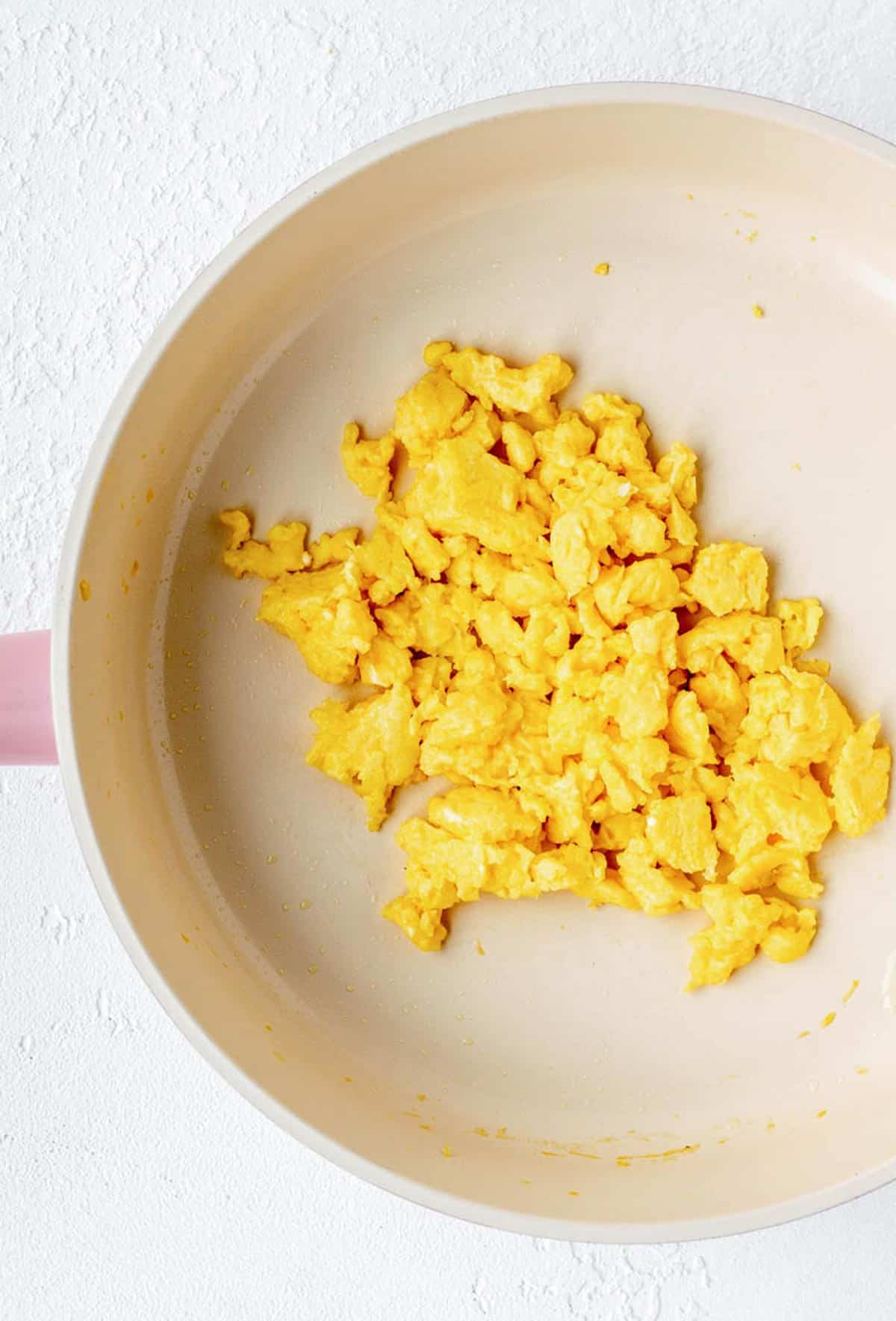 A close up of cooked scrambled eggs for baby in a frying pan.