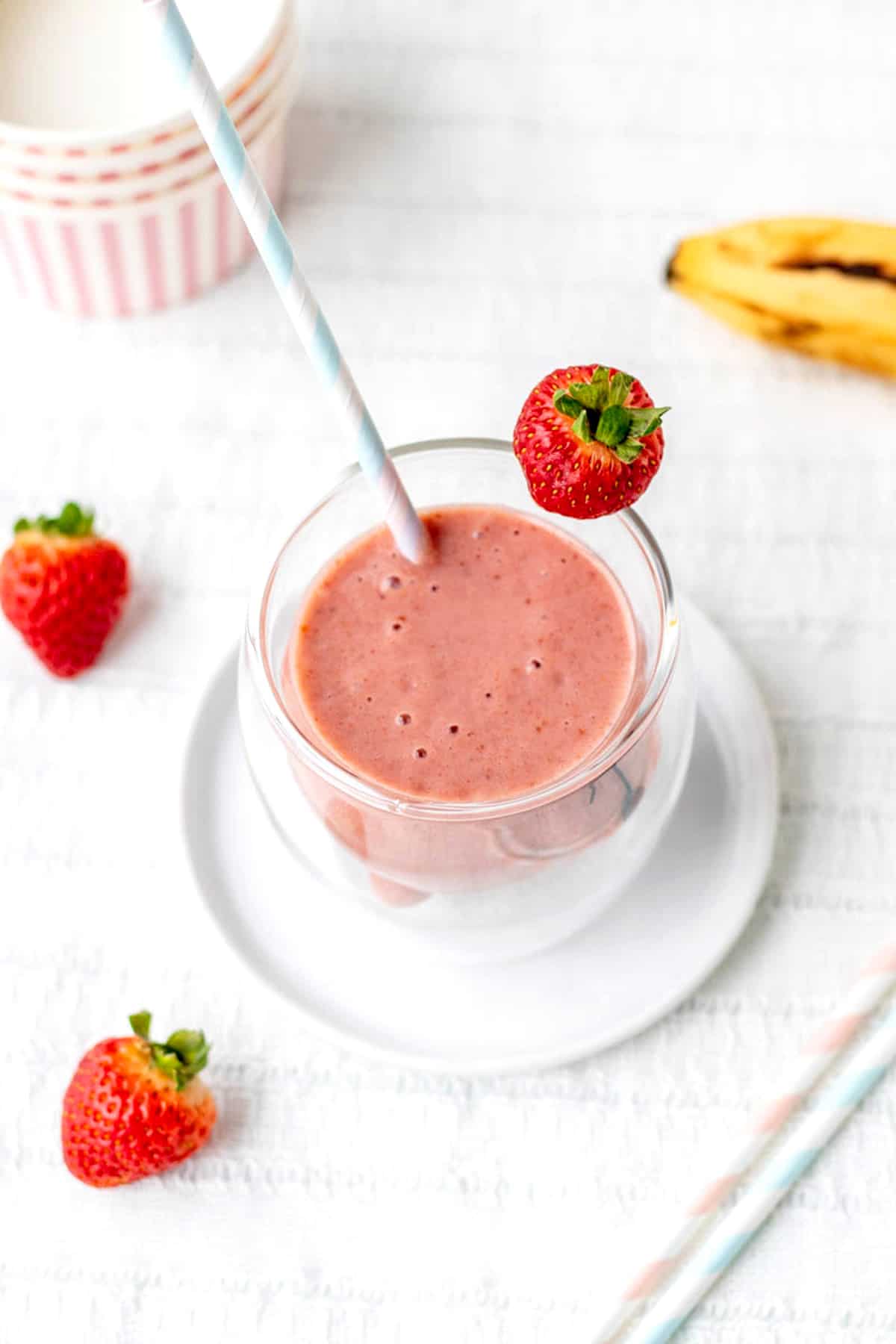 The creamy strawberry banana smoothie in a glass with a strawberry and straw.