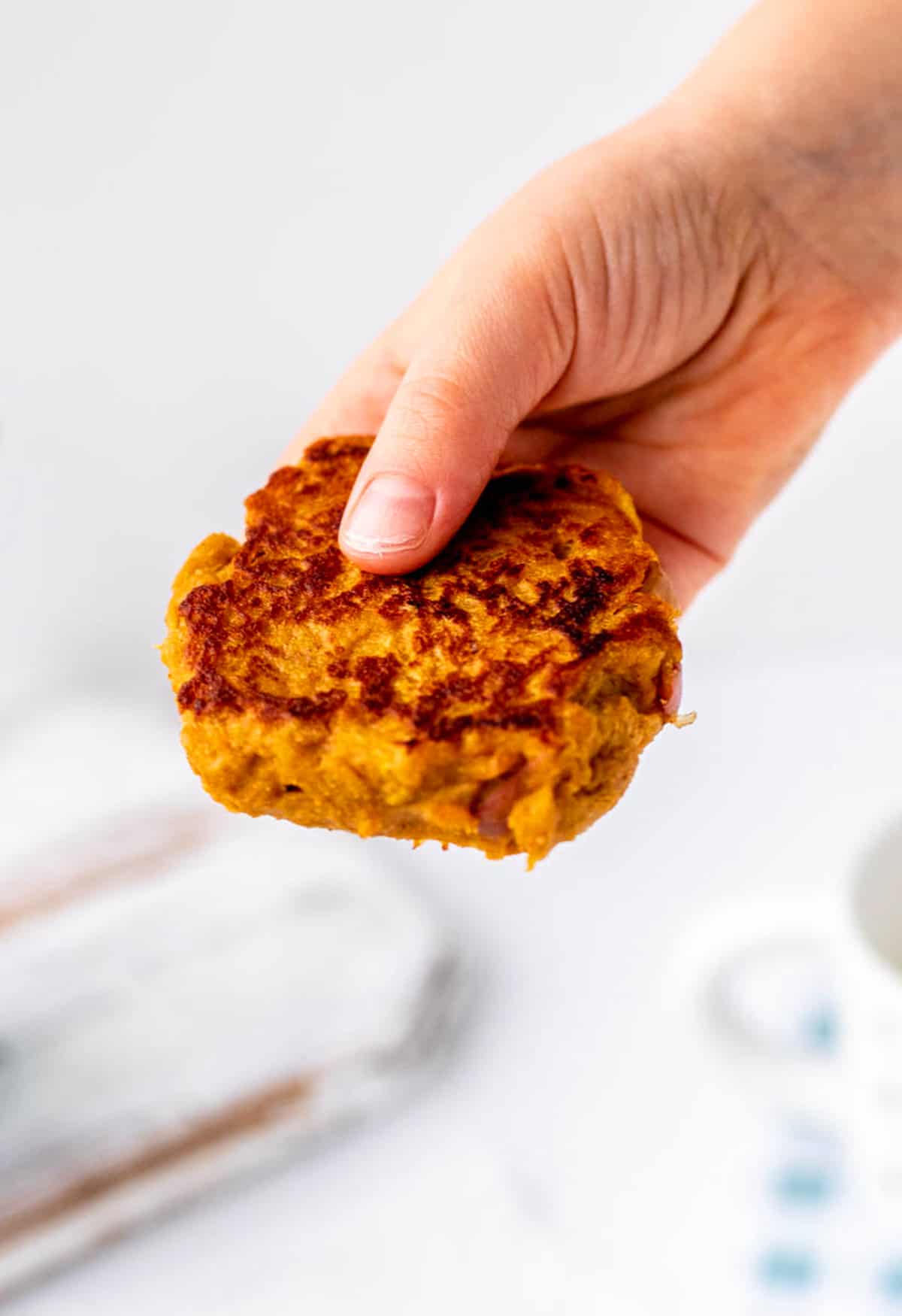 A child's hand holding a sweet potato fritter.
