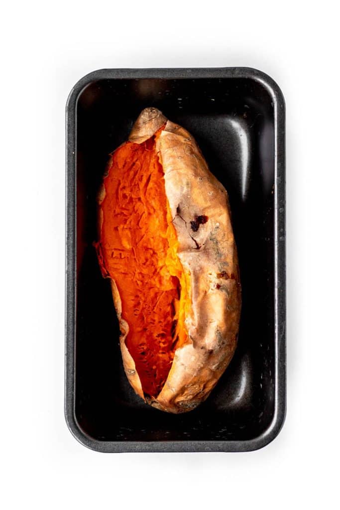A roasted sweet potato in a small baking pan.