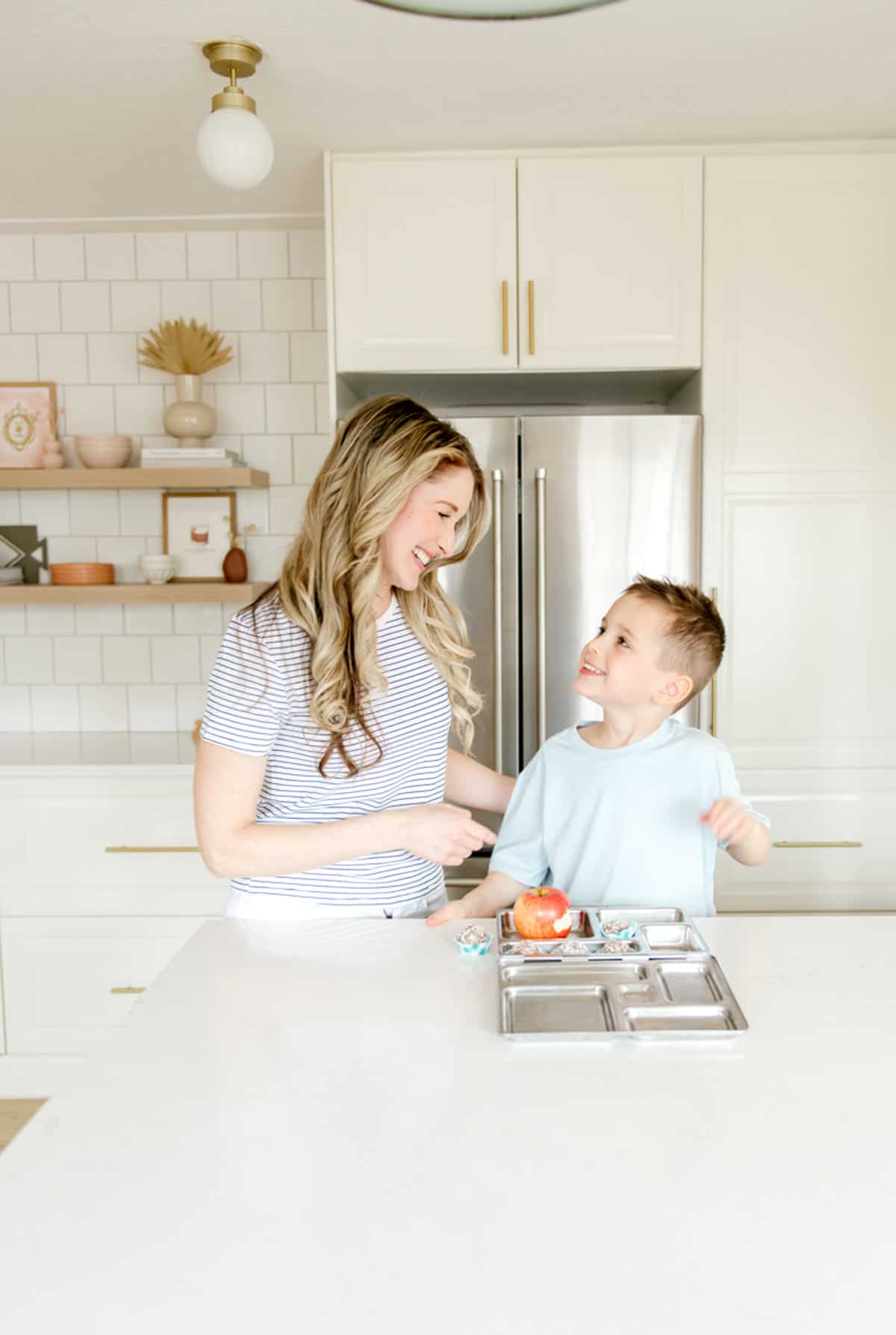 A woman and little boy packing a stainless steel lunch box.