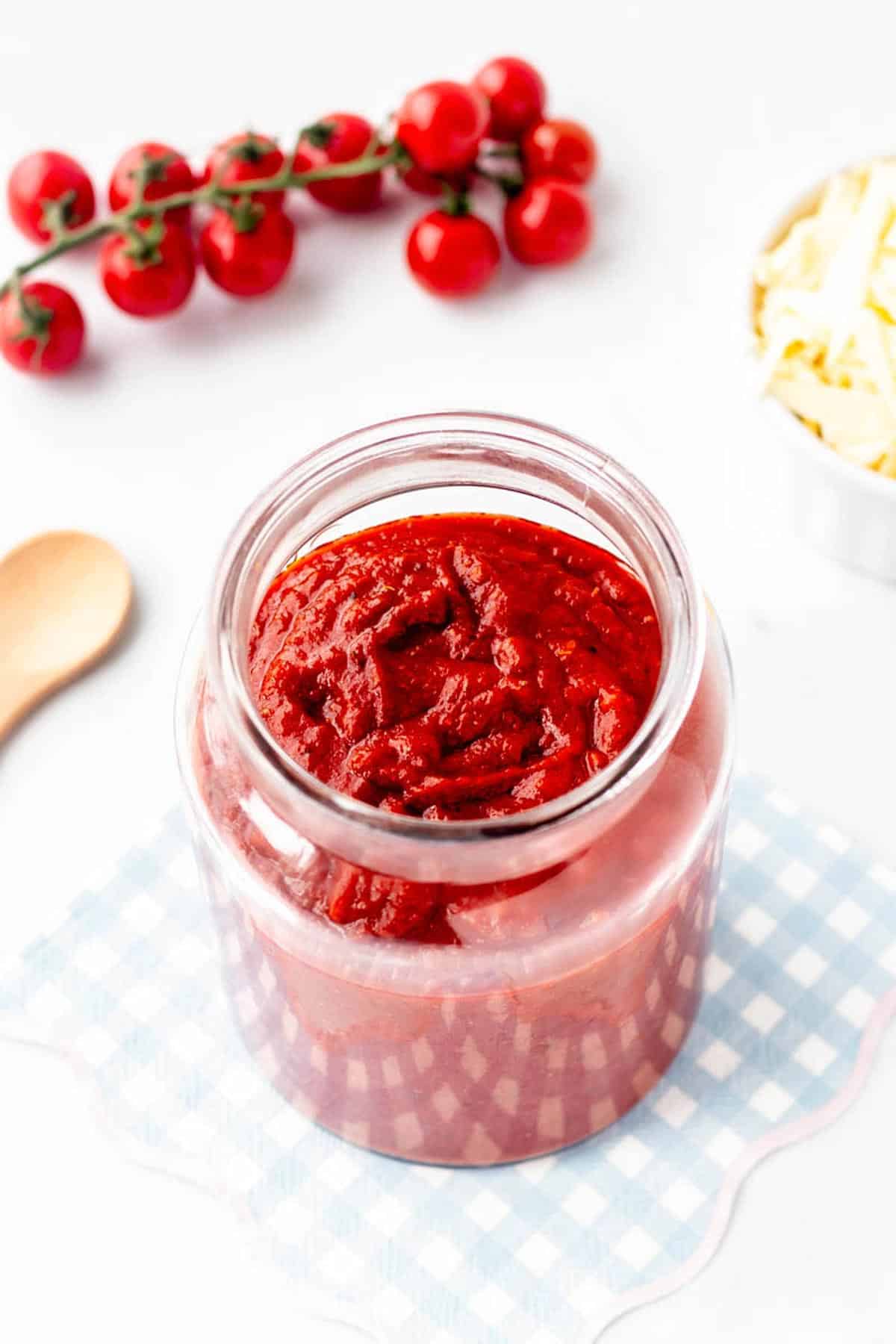 A close up image of pizza sauce in a large jar.