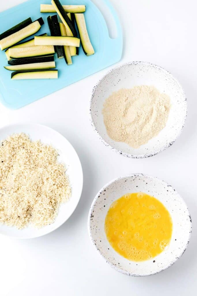 Zucchini, panko mixture, flour and eggs ready to coat zucchini fries.