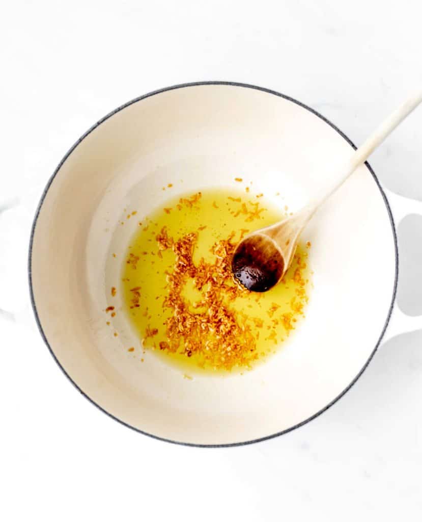 Minced garlic being sautéed in some olive oil in a large pot.