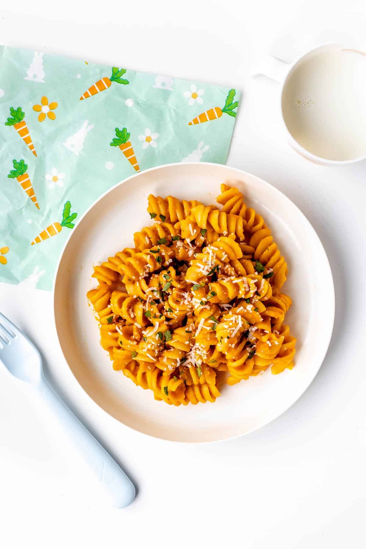 Roasted carrot pasta on a plate topped with parmesan and parsley.