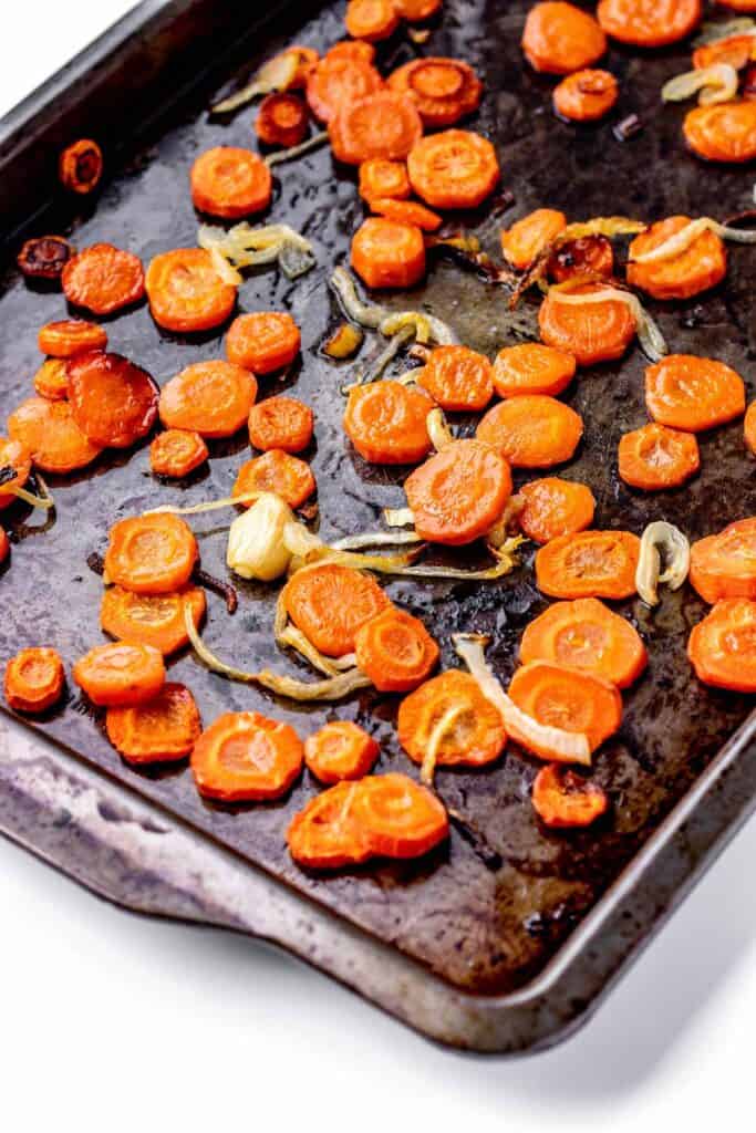 A baking sheet with roasted carrots, onions and garlic.