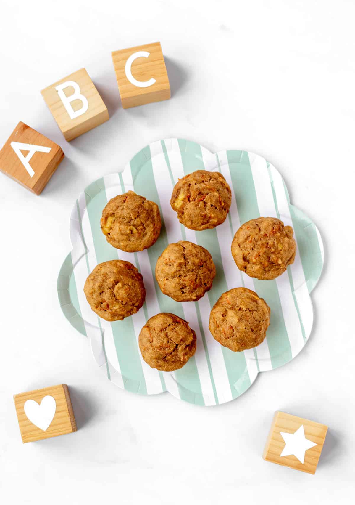 A striped plate with ABC muffins on it next to baby blocks.