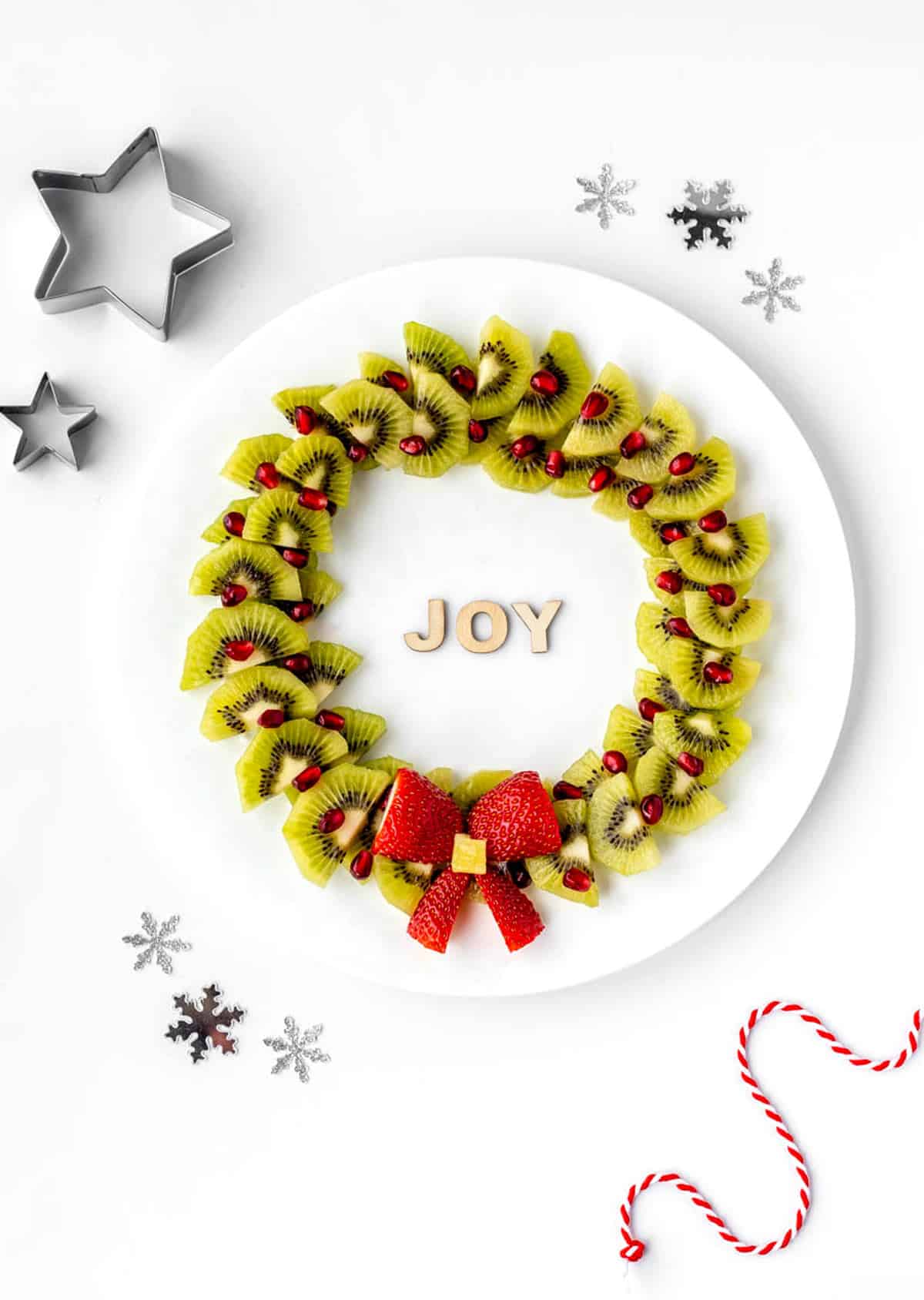 Christmas fruit wreath on a plate with the word "joy" in the middle.