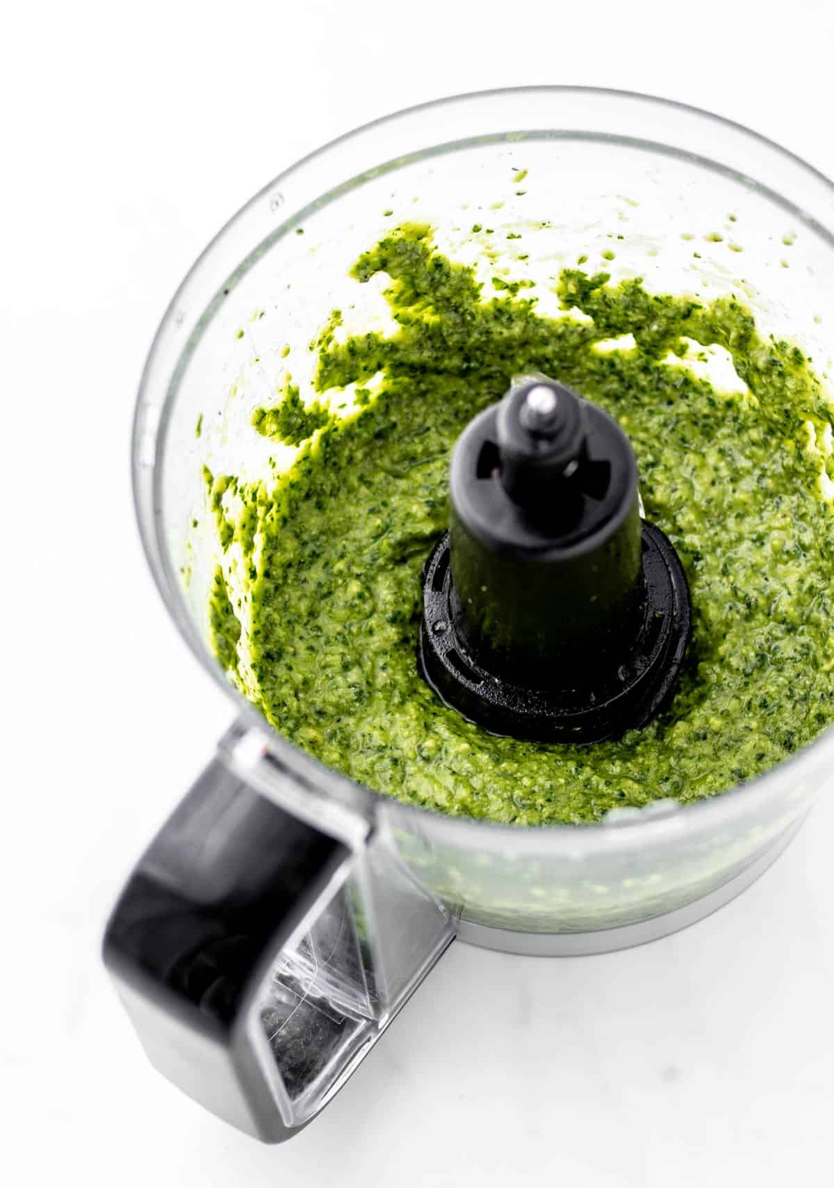 Green avocado pesto sauce in a food processor.