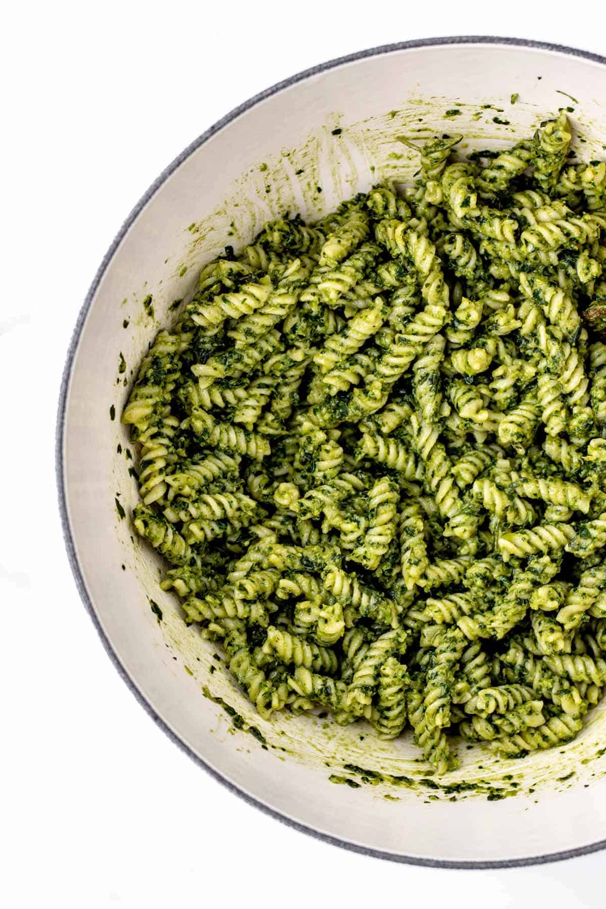 Close up image of avocado pesto sauce mixed in with pasta.