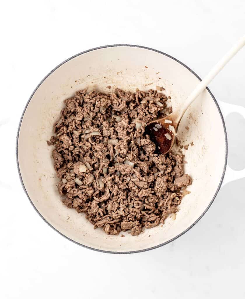 Ground beef and onion being sauteed in a large pot.