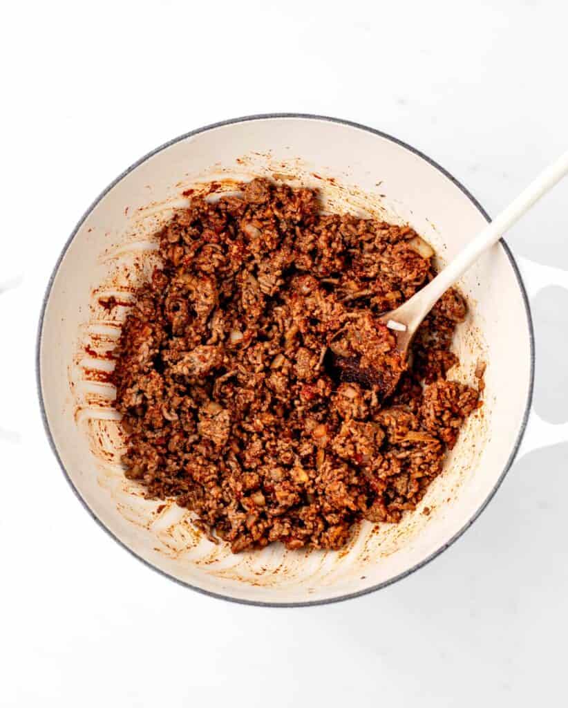 Spices and tomato paste added to the beef and onions in a large pot.