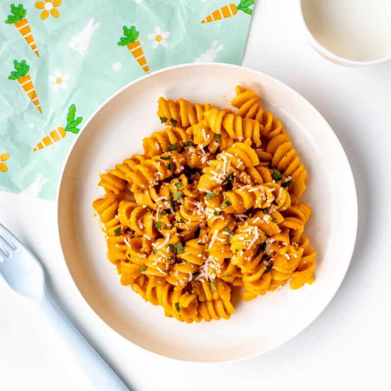 Roasted carrot pasta on a plate with a fork and napkin.