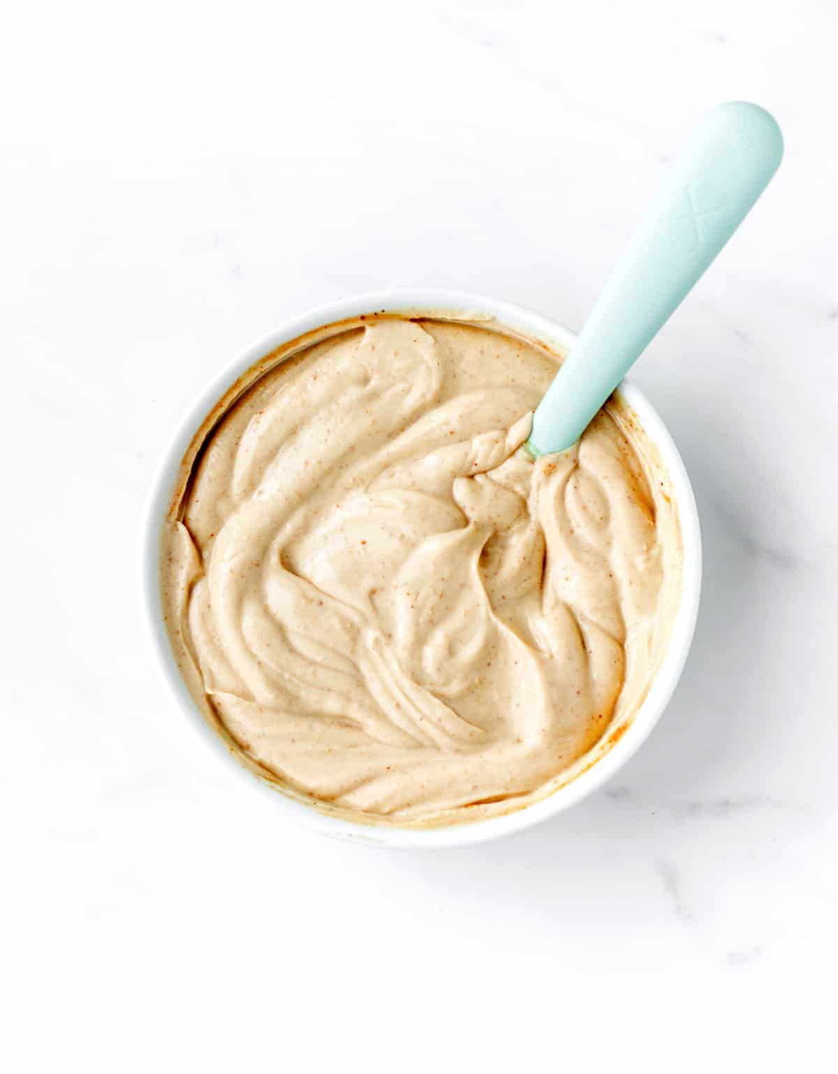 Peanut butter and yogurt dip being stirred together in a bowl.