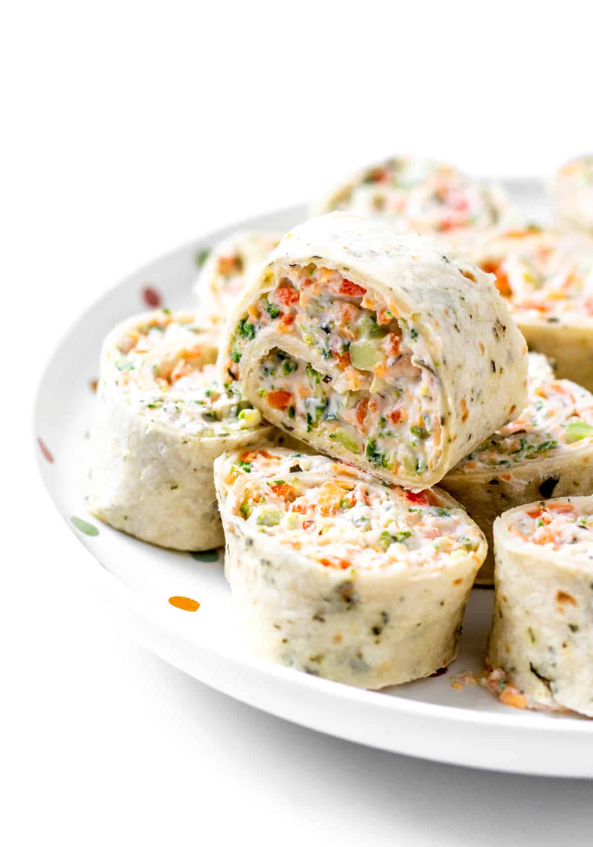 Up close image of a broccoli cheddar pinwheel on top of other roll ups.