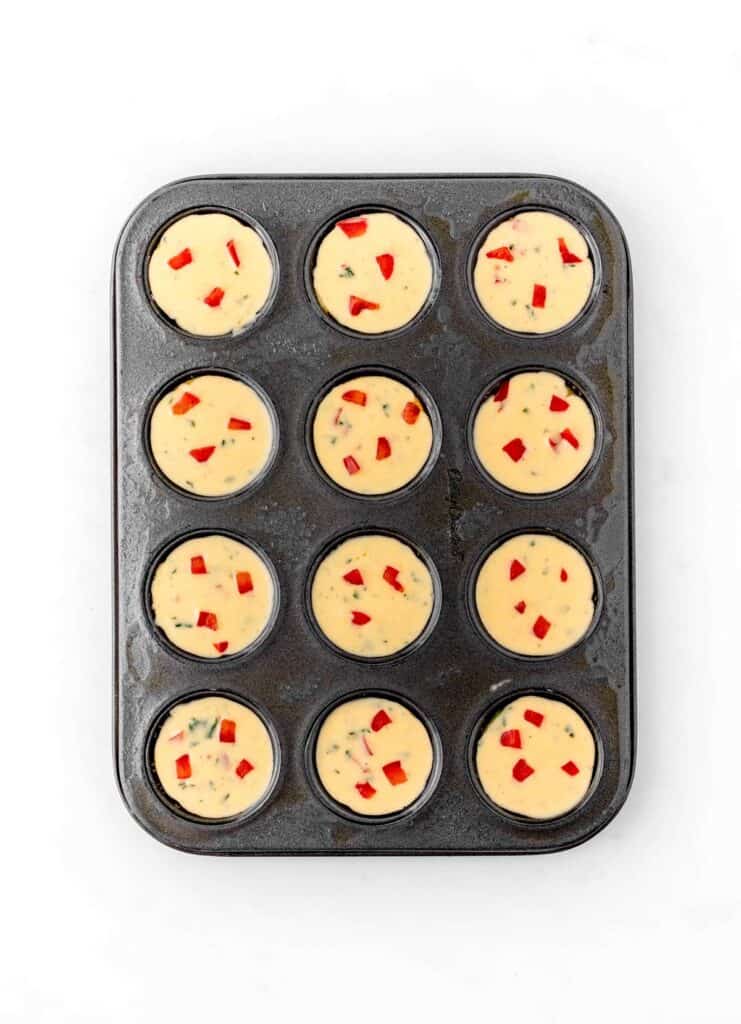 Egg mixture divided in a mini muffin tin to make egg bites.