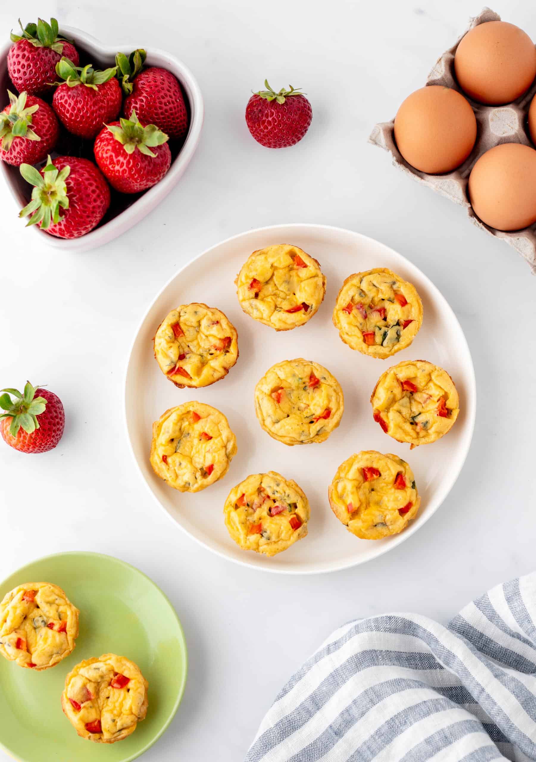 Cottage cheese egg bites on a white plate with strawberries and eggs.