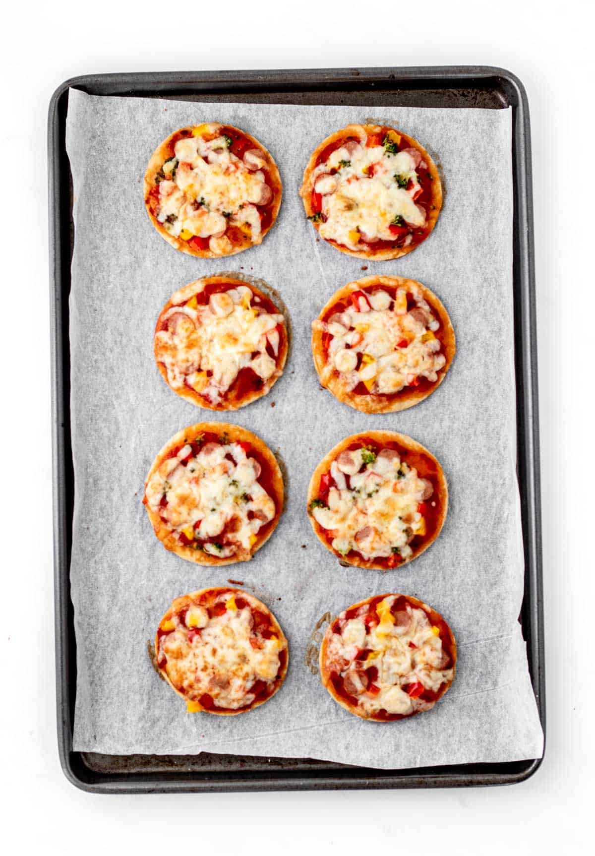 Cooked mini pizzas on a baking sheet.