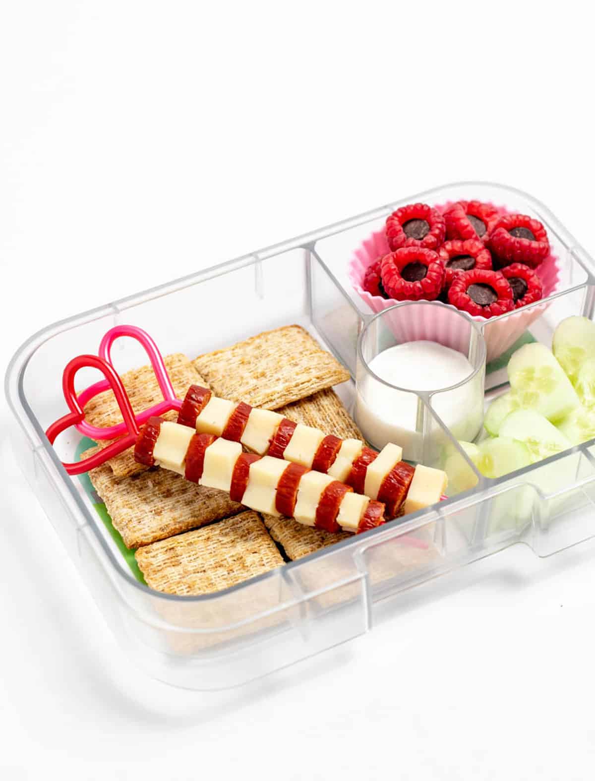 Skewers in a lunch box with crackers, chocolate stuffed raspberries and cucumbers.