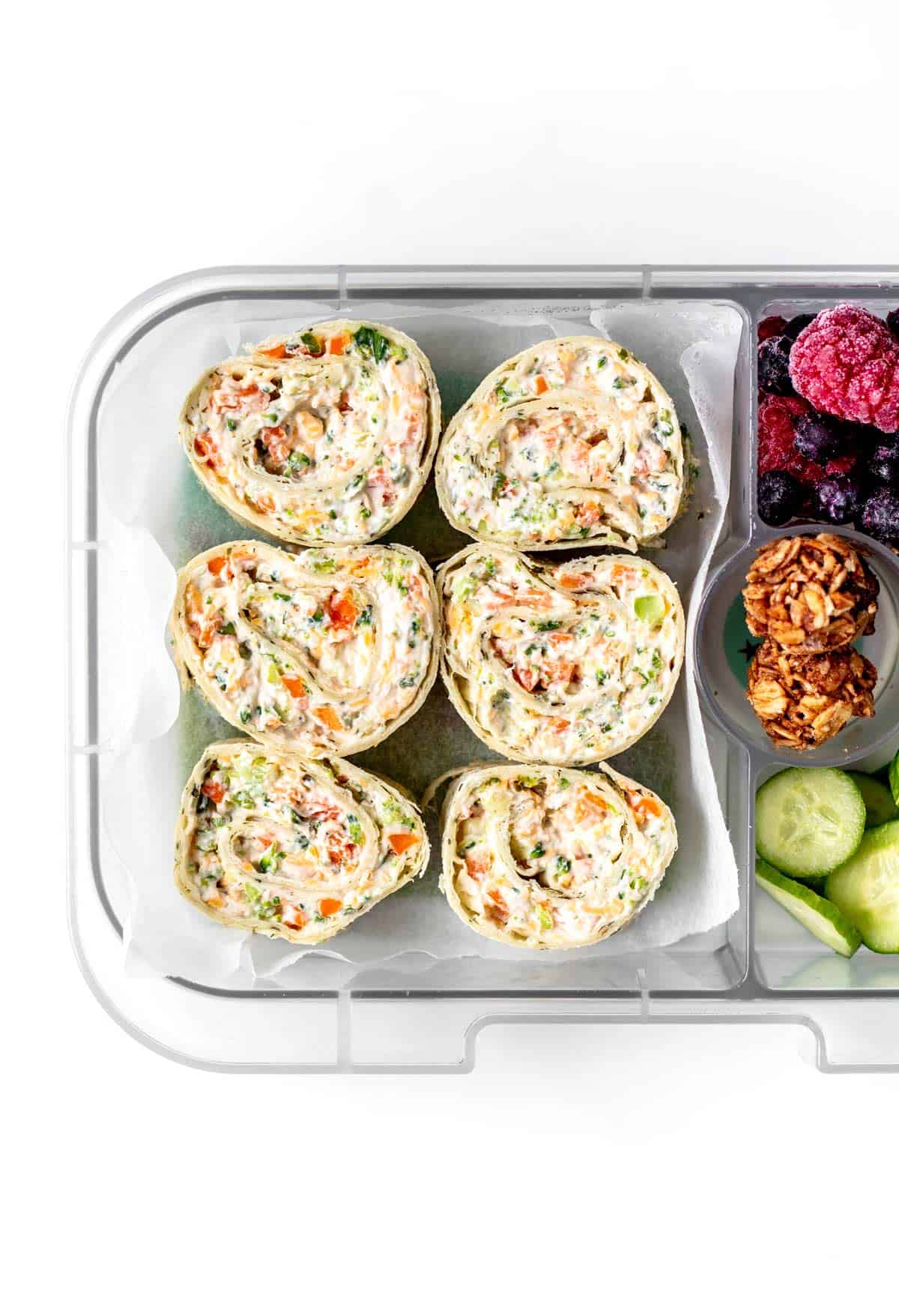 Veggie tortilla roll ups with cucumbers, berries and granola bites.