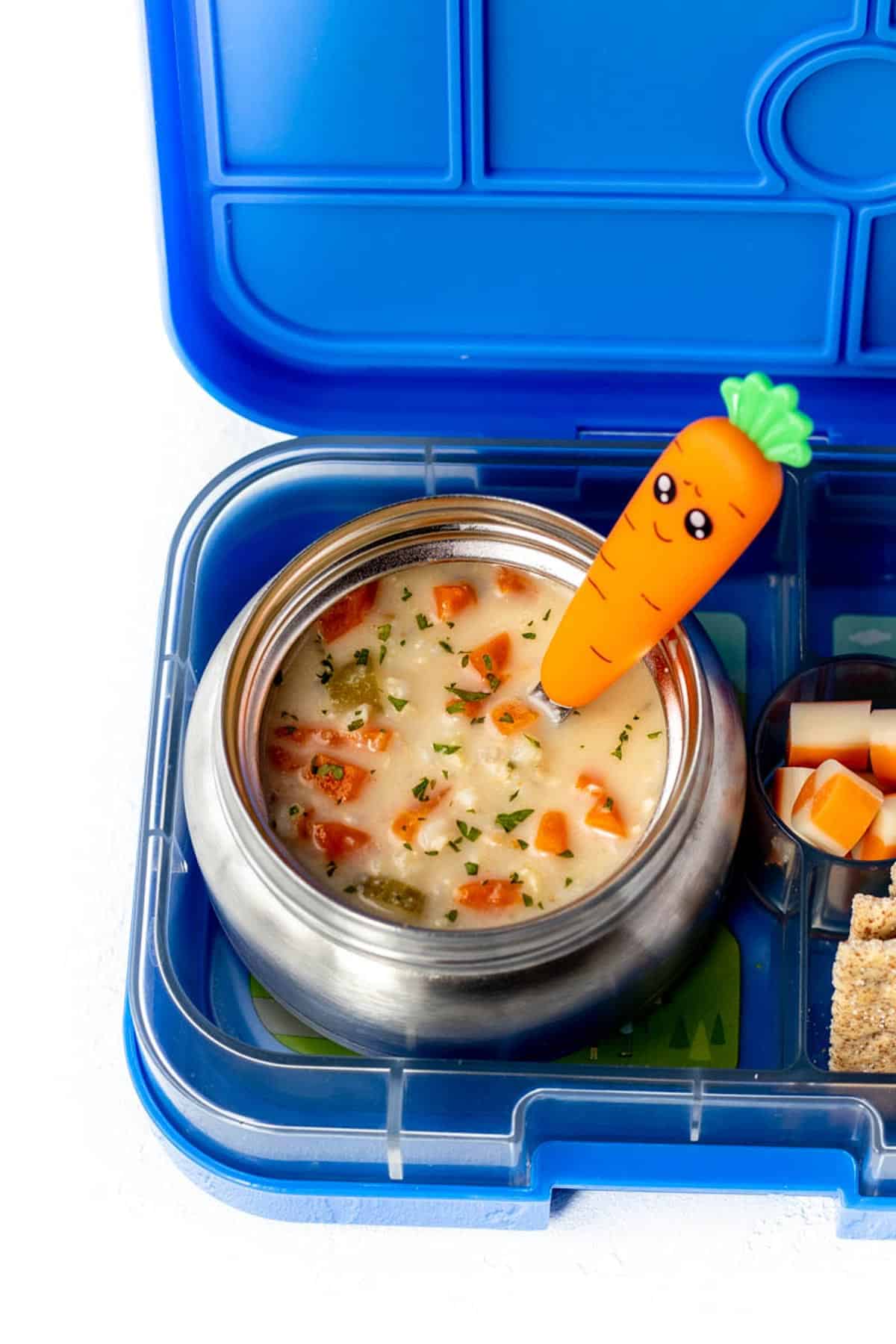 Soup in a thermos with a carrot spoon.