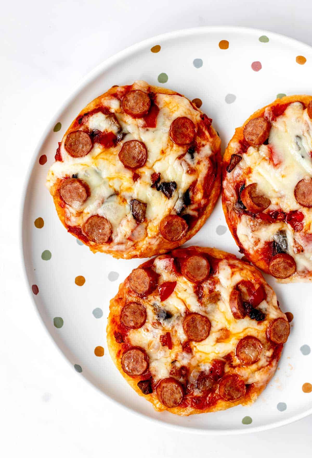 Three mini Greek yogurt pizzas on a polka dot plate.