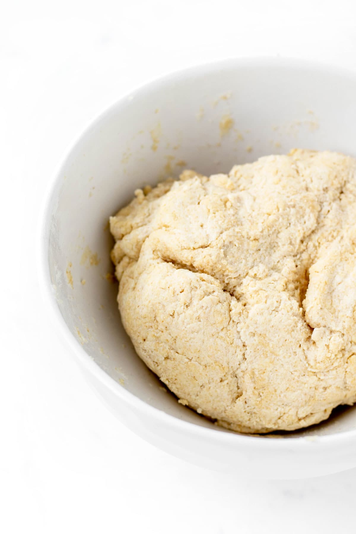 Close up of pizza dough recipe with Greek yogurt in a white bowl.