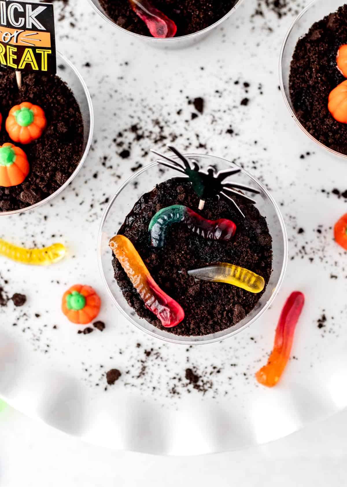 Overhead image of Halloween dirt cups with gummy worms and candied pumpkins.