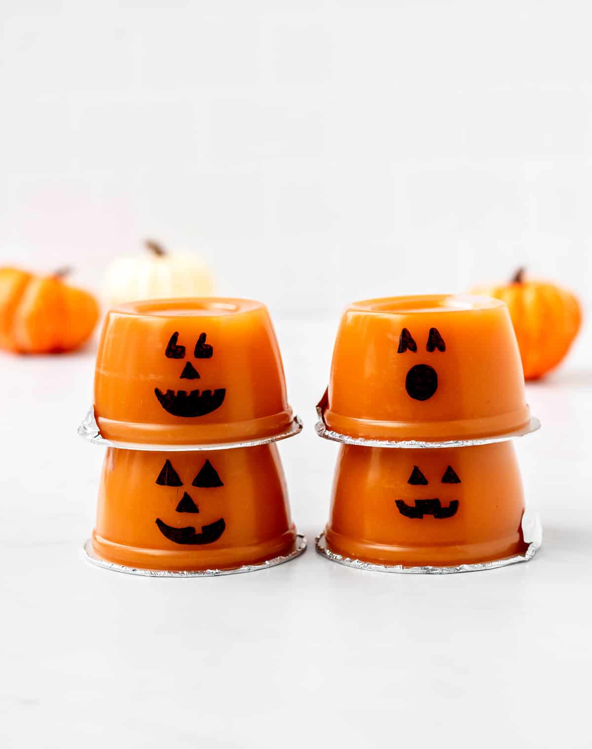 Four jack o lantern applesauce cups stacked on top of each other.