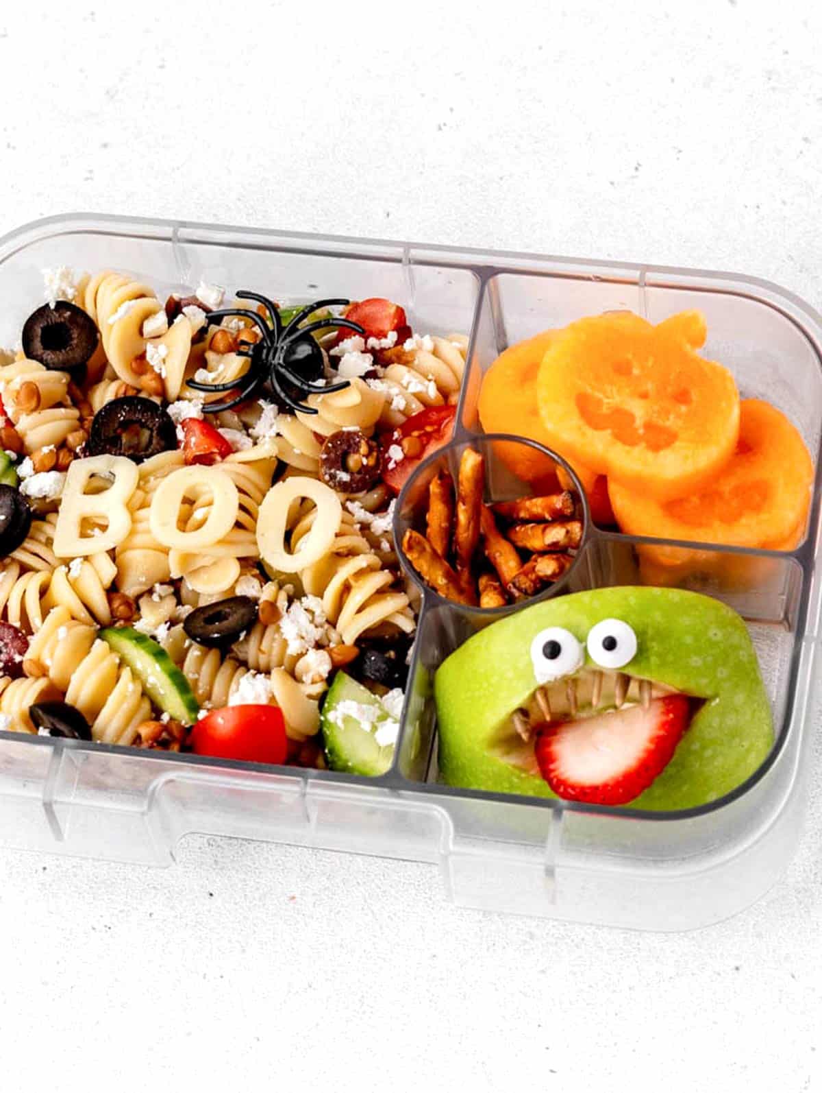 Cantaloupe pumpkins, apple monster and Halloween pasta salad in a lunch container.