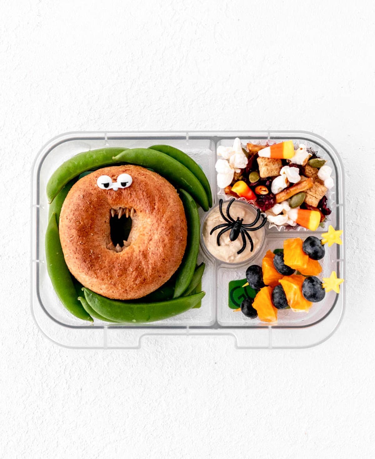 Halloween lunch box with monster bagel, halloween fruit kabobs and halloween trail mix.