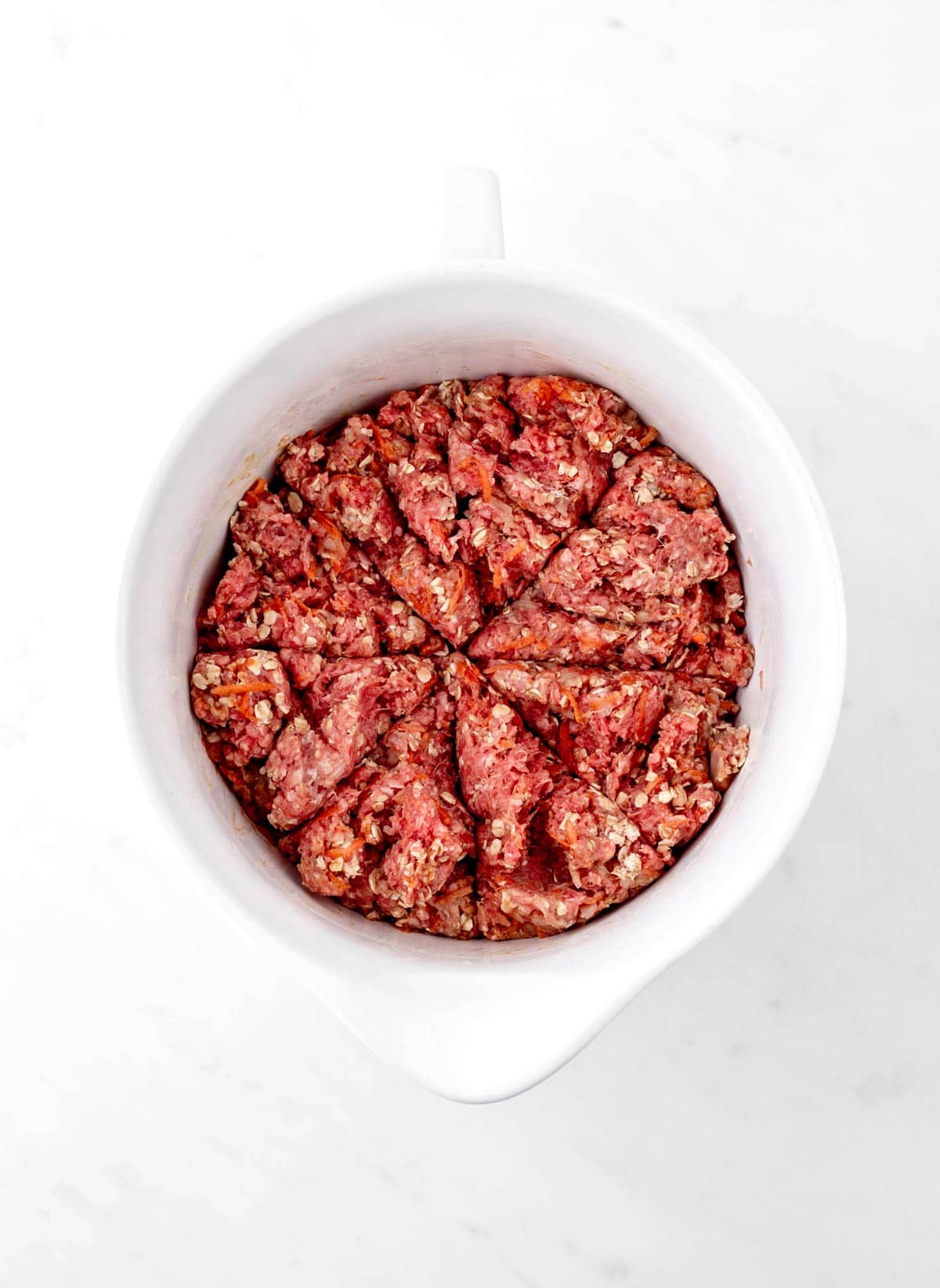 Meatloaf mixture in a bowl divided into eight sections to make mini meatloaf recipe.