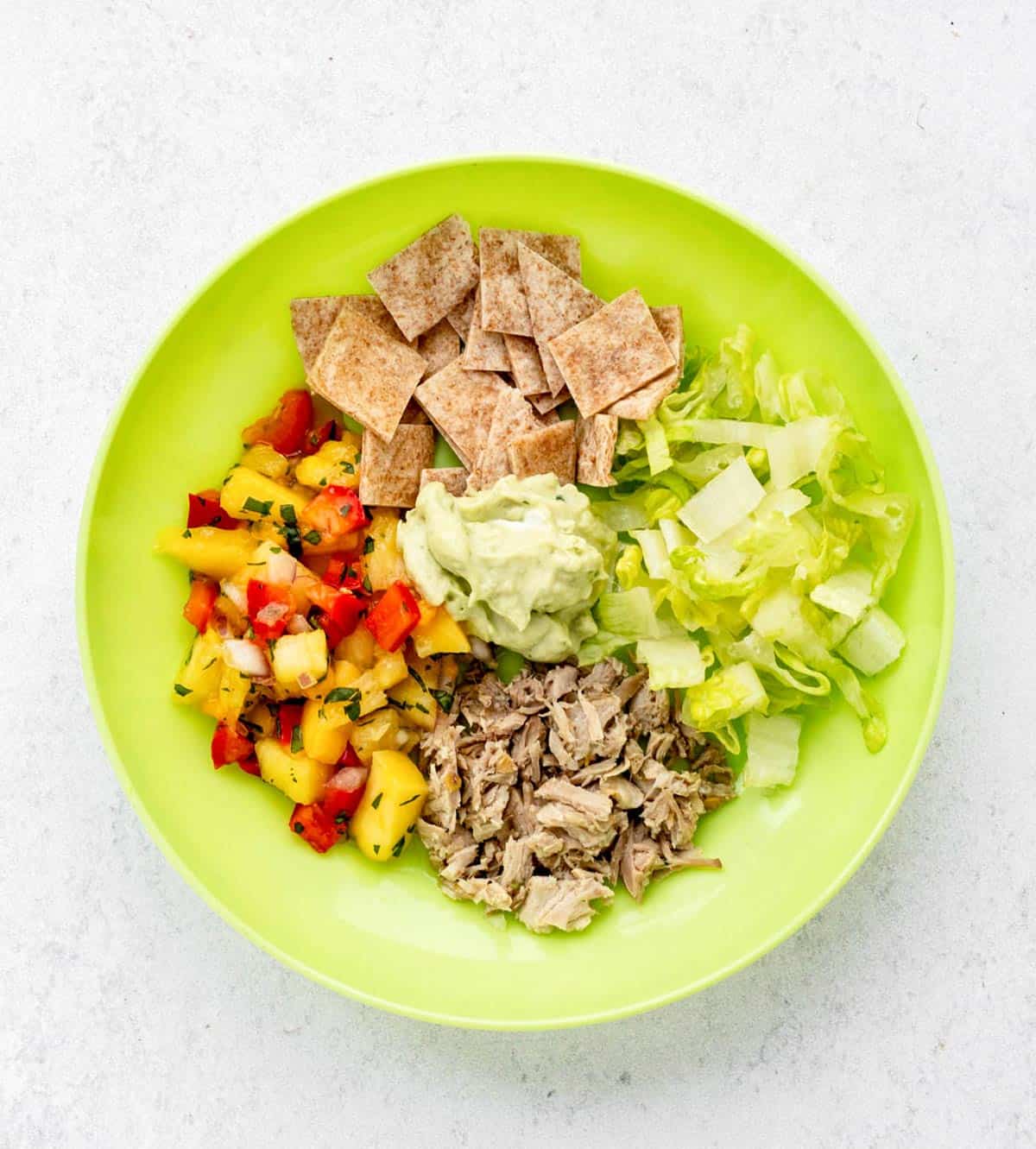 Pulled pork taco bowl with salsa, wraps, lettuce and avocado crema.