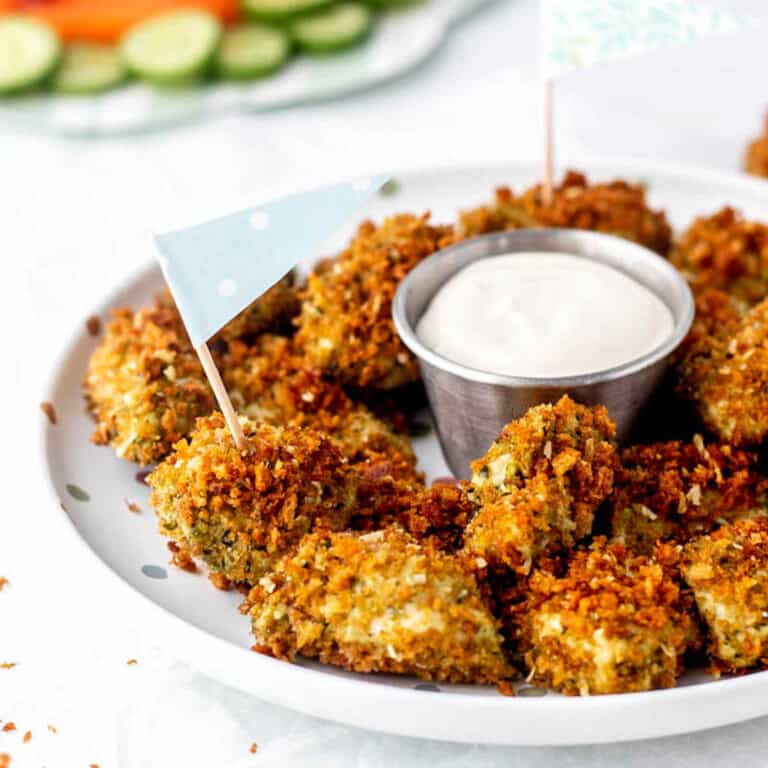 A plate of pesto chicken bites with flags and dip.