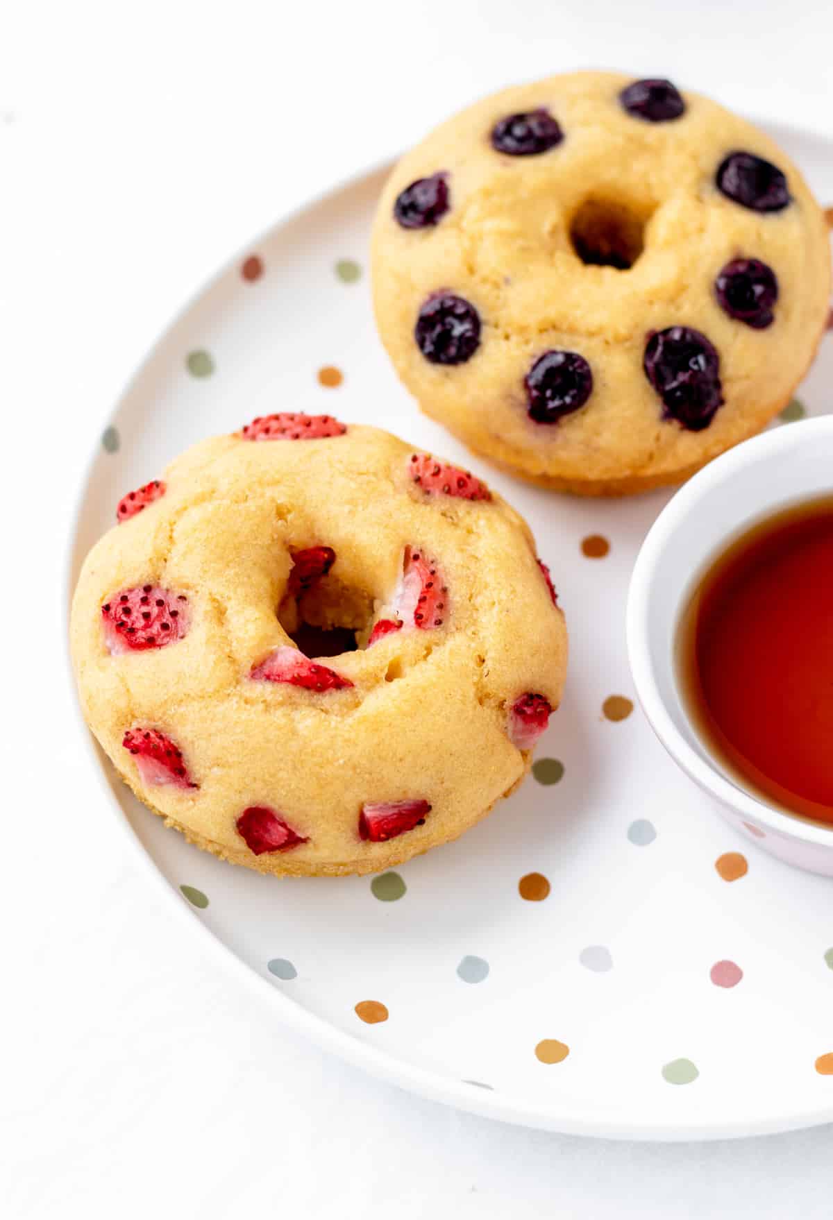 Two pancake donuts on a plate with maplesyrup.