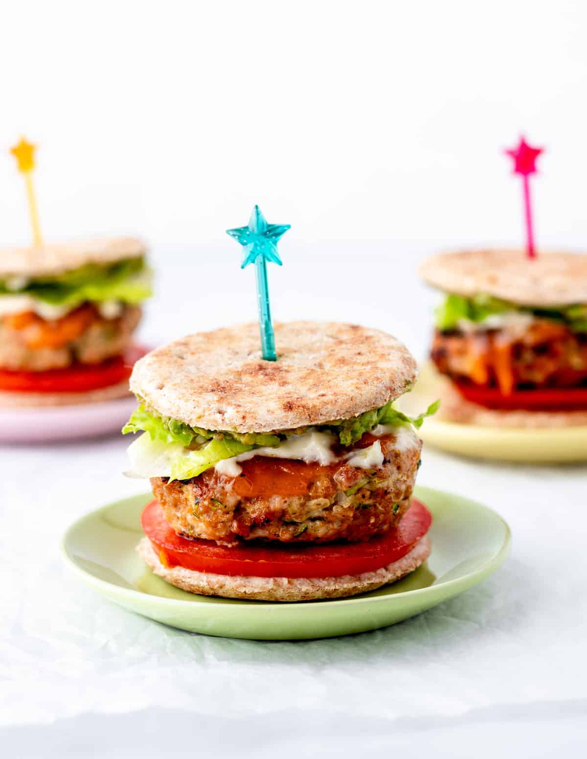 Three turkey burger sliders on mini plates with star picks.