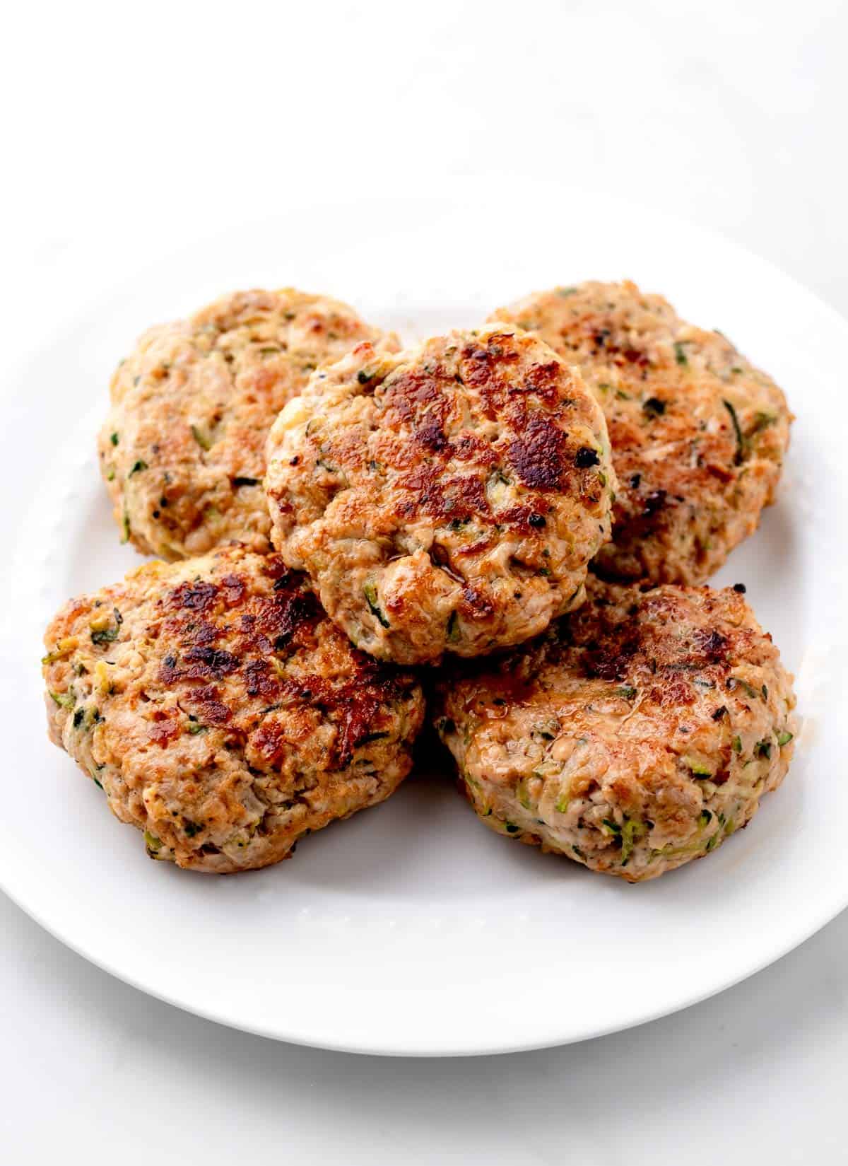 Mini turkey burger sliders stacked on a plate.