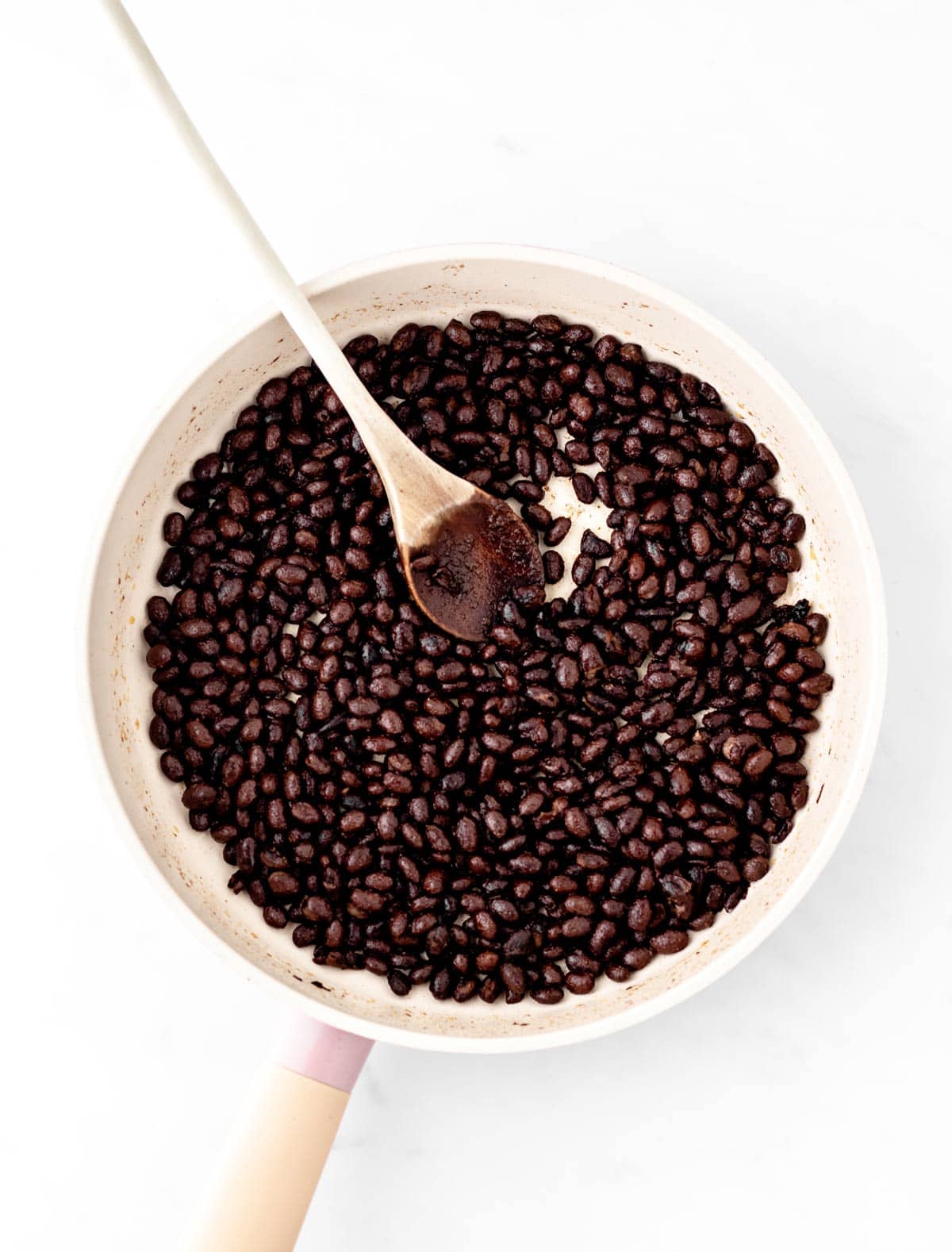 Black beans in a skillet with a spoon.