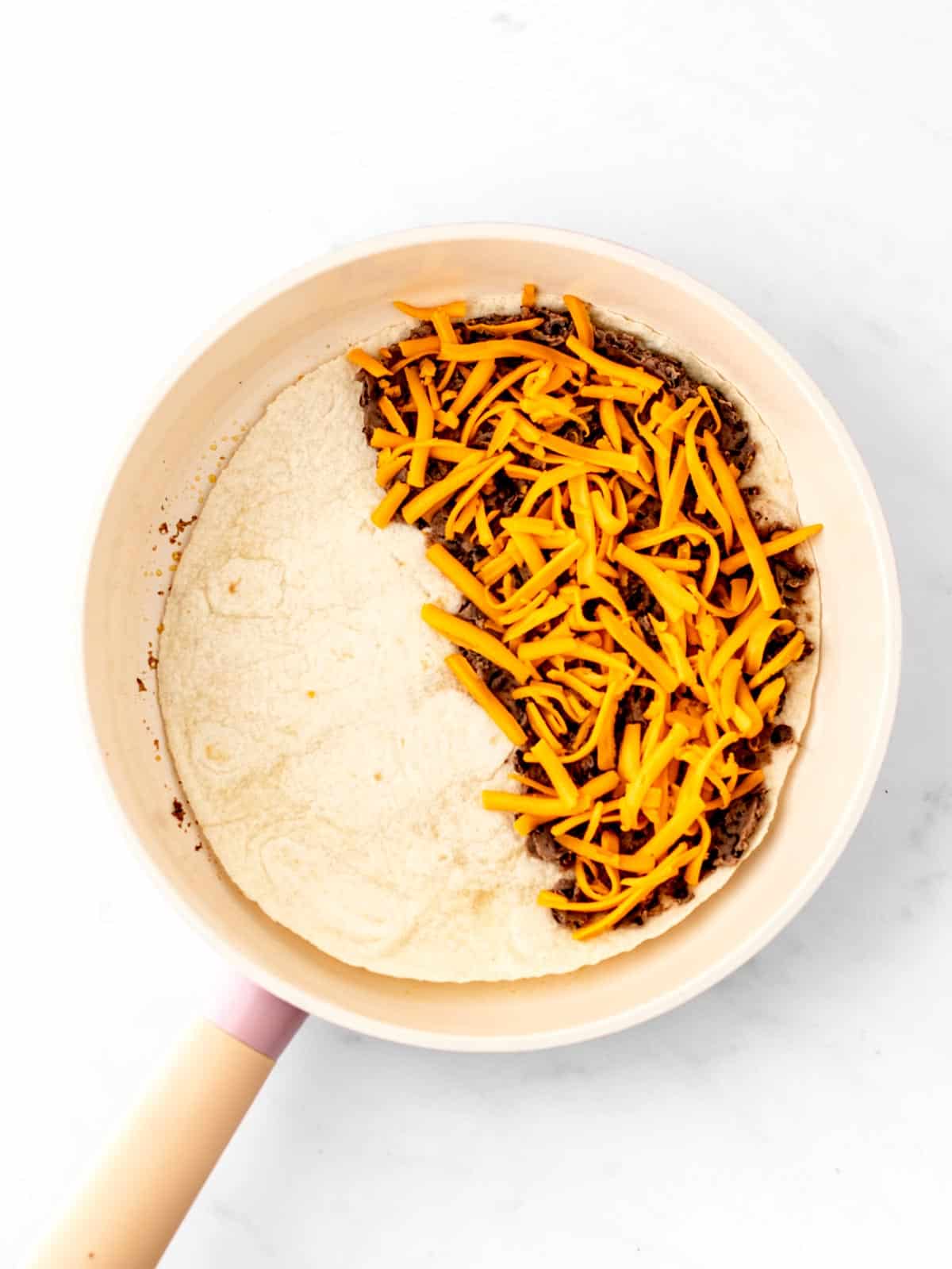 Ingredients for making black bean and cheese quesadillas in a skillet.