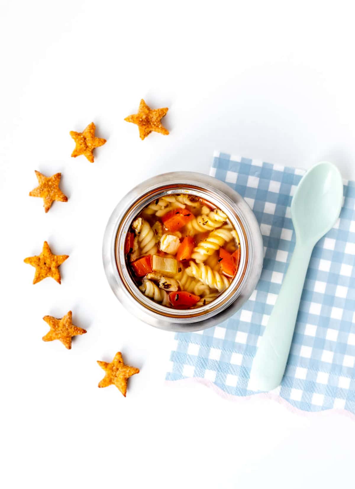 An overhead image of soup in a thermos with crackers.