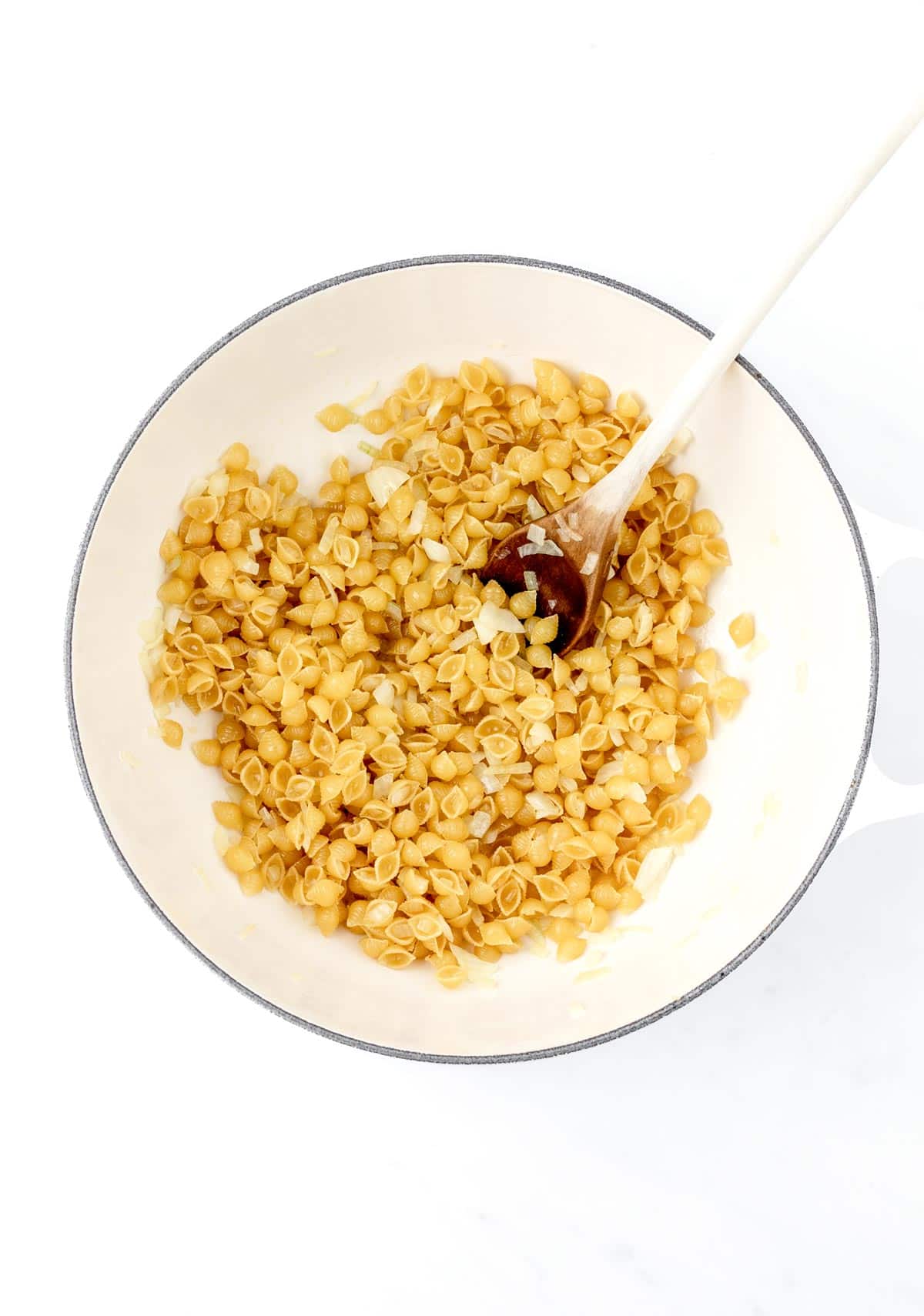 Dry shell noodles in a white bowl with a spoon.