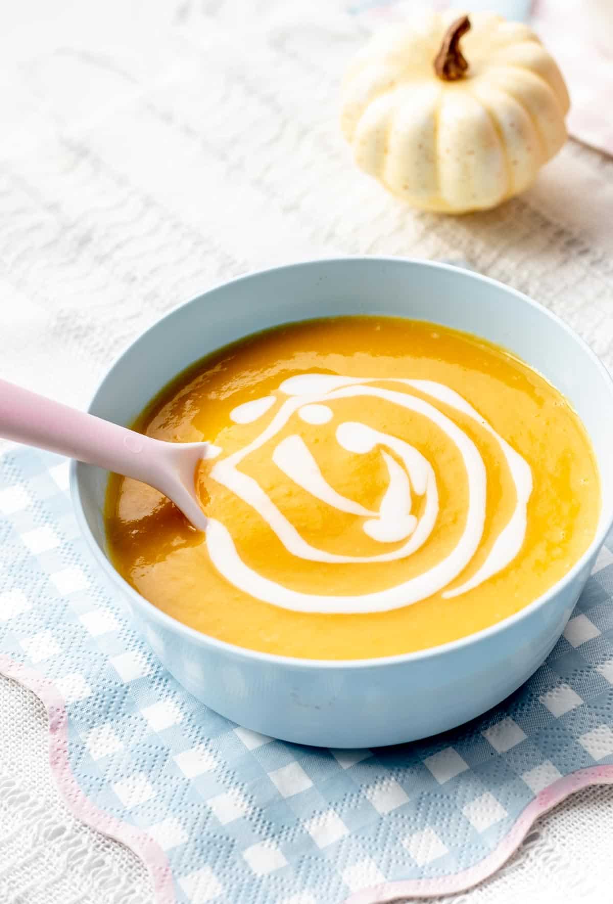 A light blue bowl filled with pumpkin soup for babies.