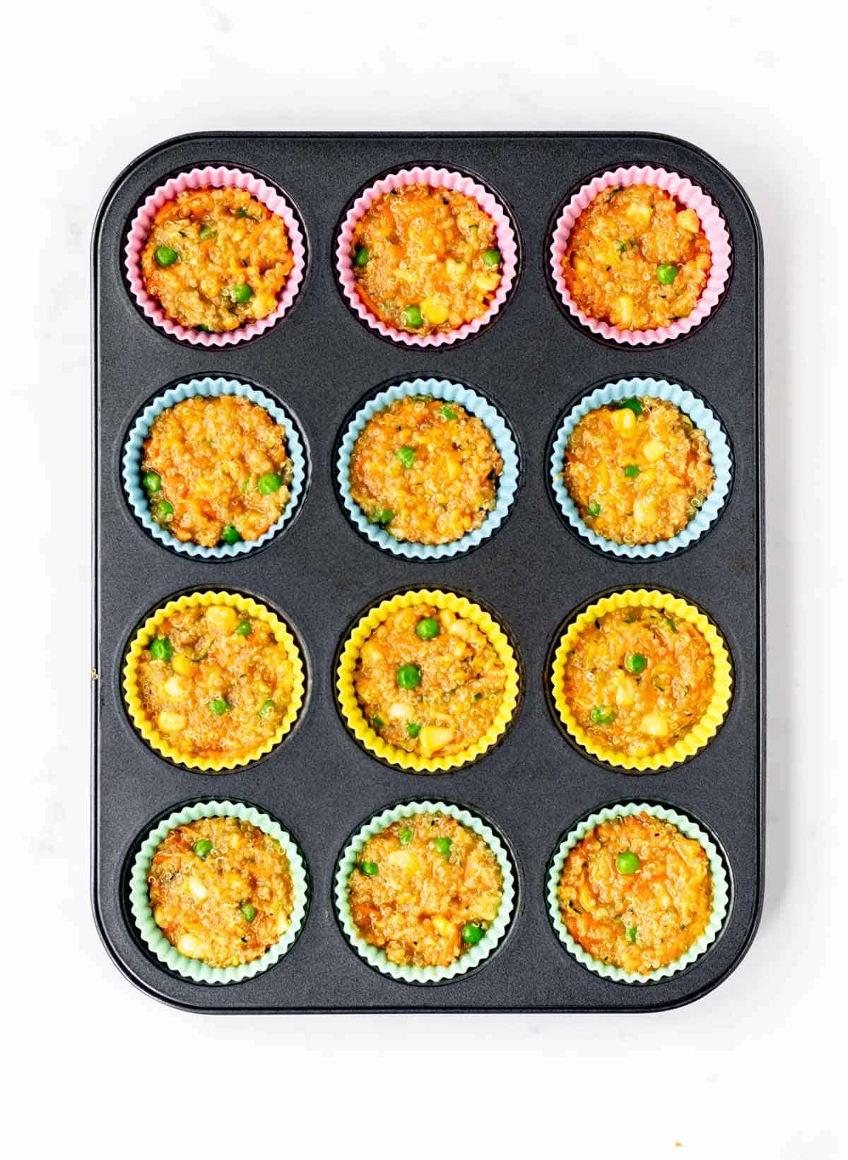 Uncooked quinoa veggie bites in silicone liners in a muffin tin.
