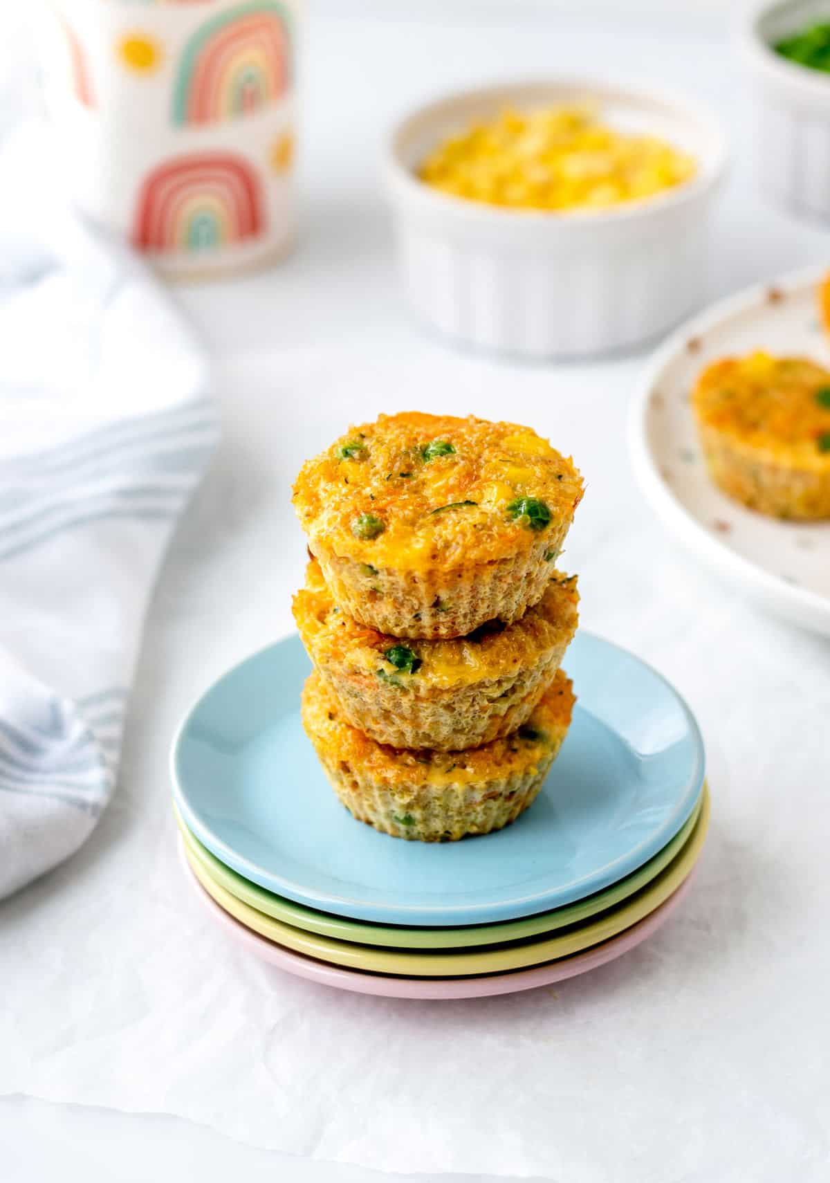 Veggie quinoa muffins stacked on top of each other on some small plates.